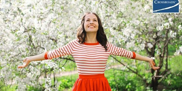 woman smiling in blooming trees empowered to overcome addiction
