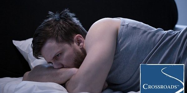 man laying in bed with alcohol disrupting his sleep