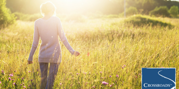 woman walking in field and embracing nature as part of addiction recovery