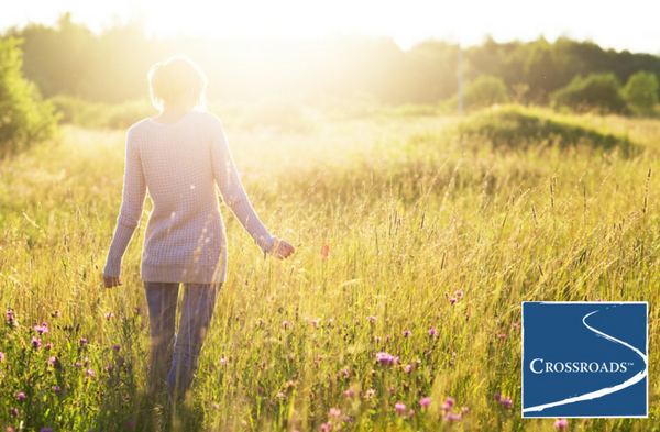 woman walking in field and embracing nature as part of addiction recovery