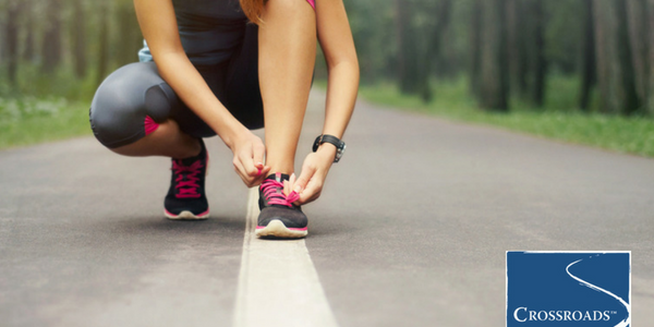 woman tying running shoes along path to increase motivation in recovery