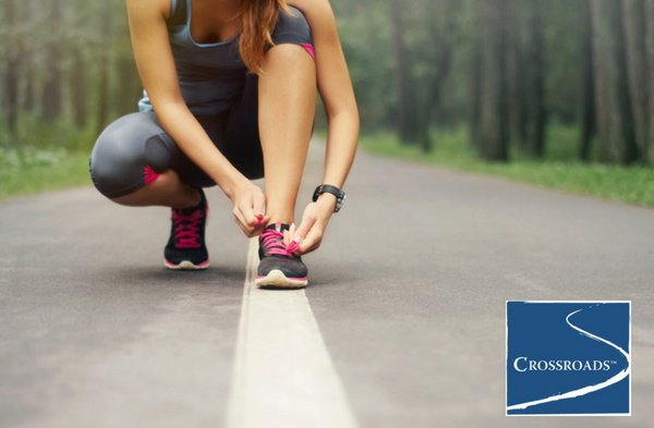 woman tying running shoes along path to increase motivation in recovery