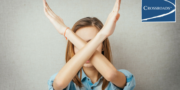 young woman crossing arms in an X to say no to boredom in recovery