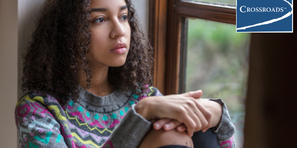 teen girl sitting depressed by window because of avoidant and restrictive food intake disorder