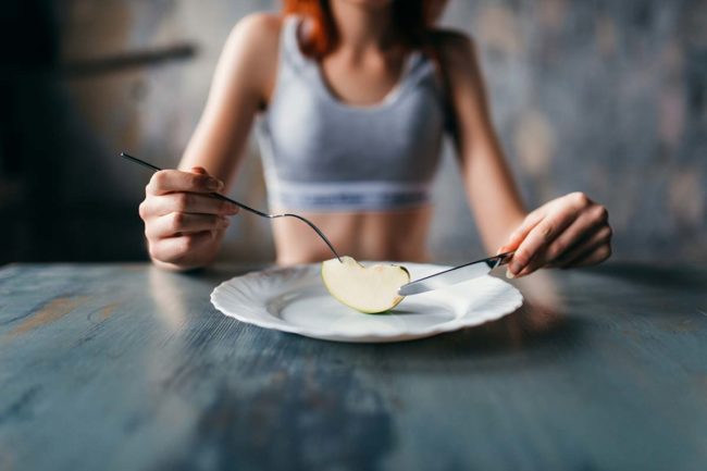 woman staring at food wondering about anorexia vs bulimia