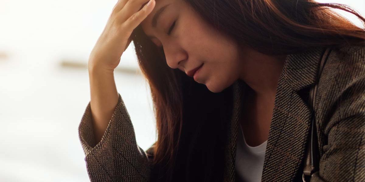a woman puts her head in her hand as she struggles with anxiety and alcohol