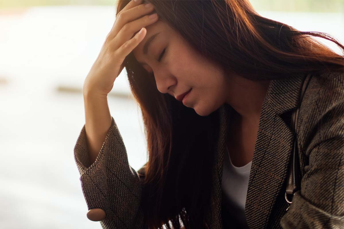 a woman puts her head in her hand as she struggles with anxiety and alcohol