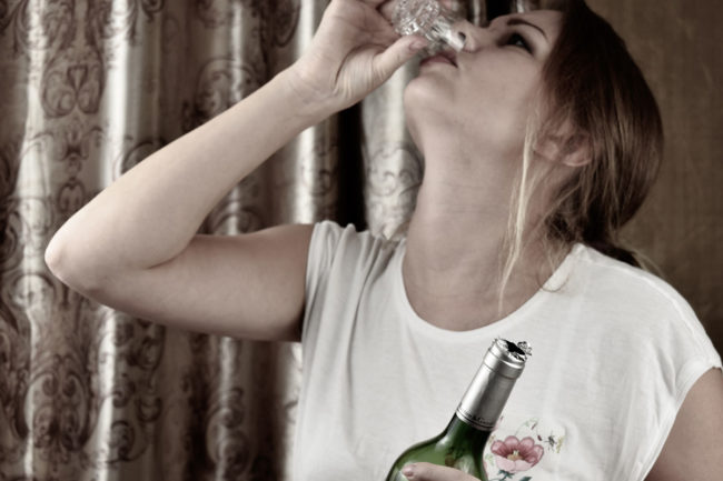 a woman drinks and thinks about the dangers of alcohol addiction