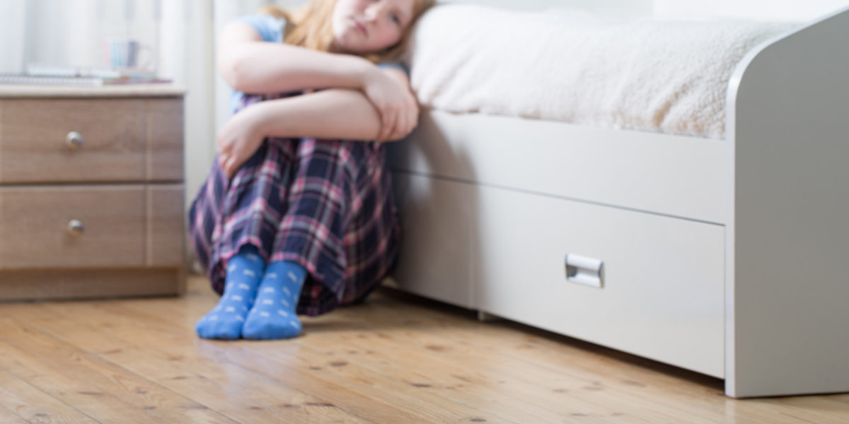 a young girl sits on the floor of her bedroom as she considers body image and social media