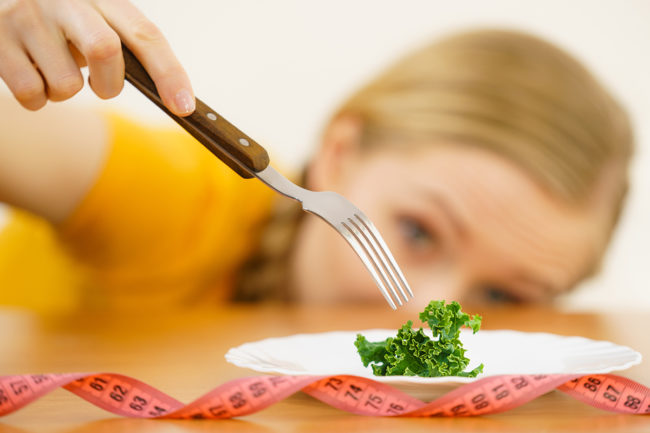 a woman prepares to eat a piece of lettuce as she considers a clean eating disorder
