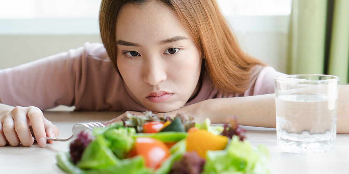 eating disorder causes a woman stares at a salad and wonders about eating disorder causes