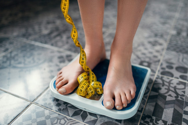 a woman weighs herself as she considers eating disorder statistics