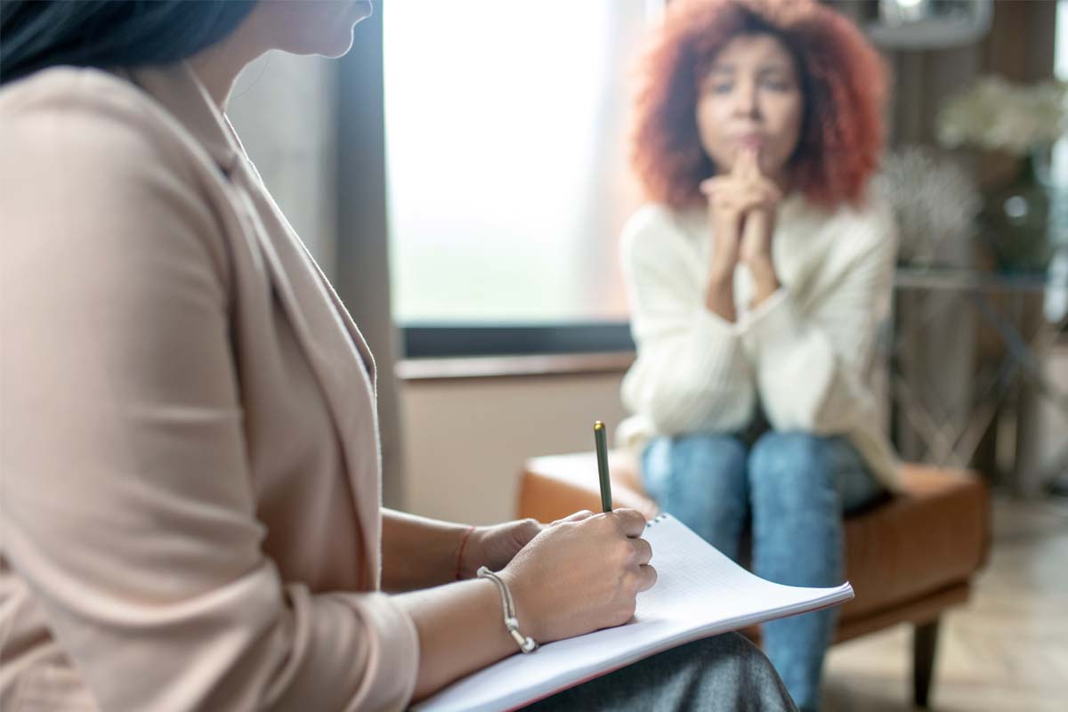 a woman talks to her therapist about attending a treatment program for addiction