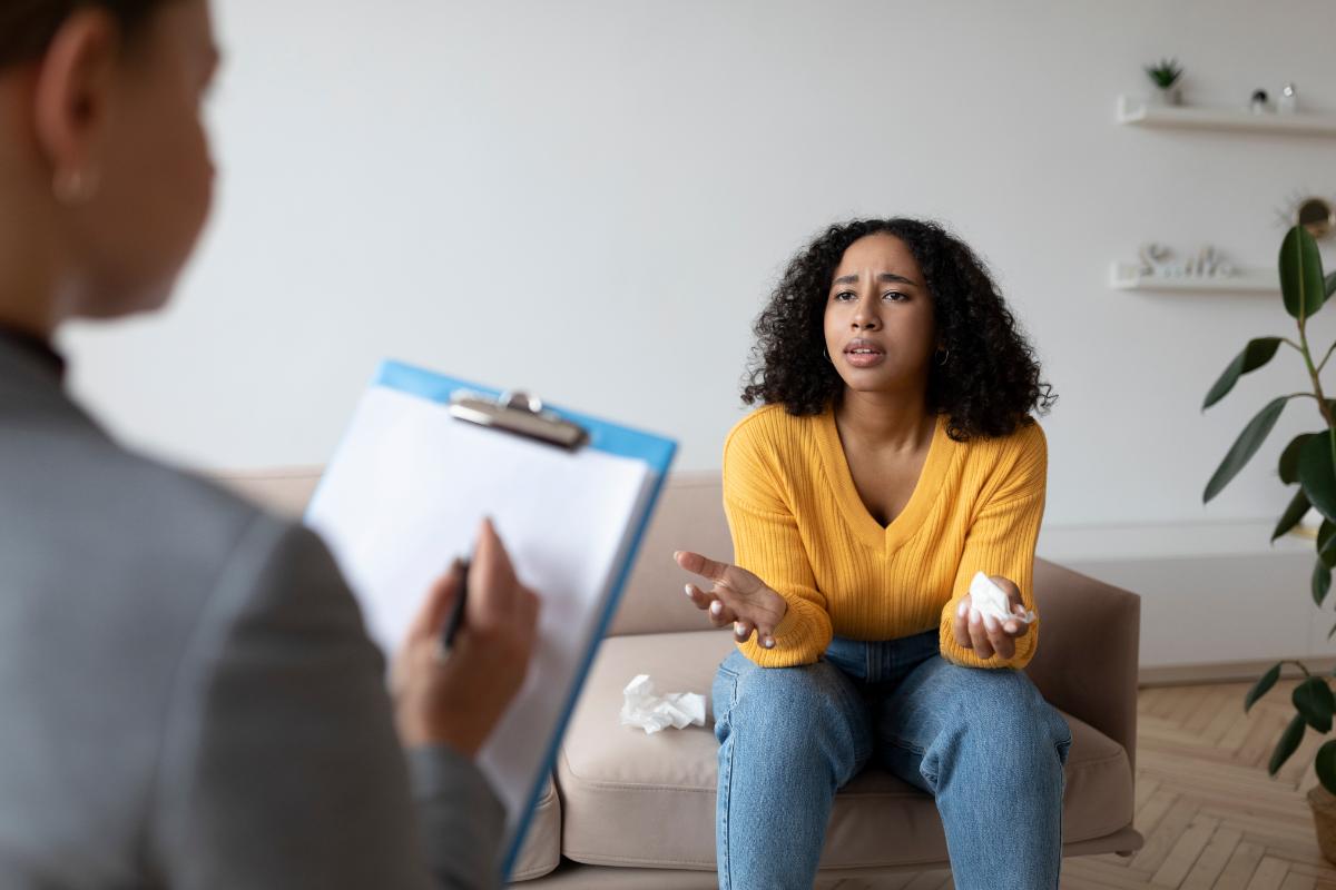 a woman talks to a therapist about trauma-informed alcohol addiction therapy