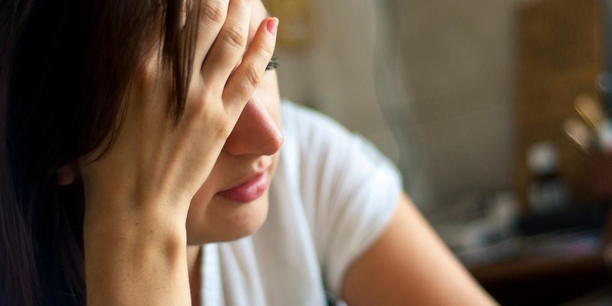 woman sitting with hand to her forehead learning about heroin addiction symptoms