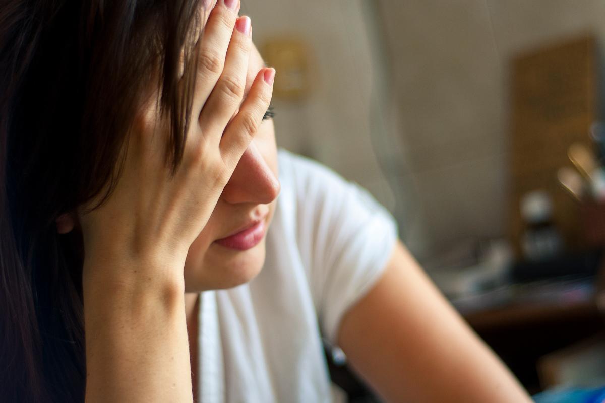 woman sitting with hand to her forehead learning about heroin addiction symptoms
