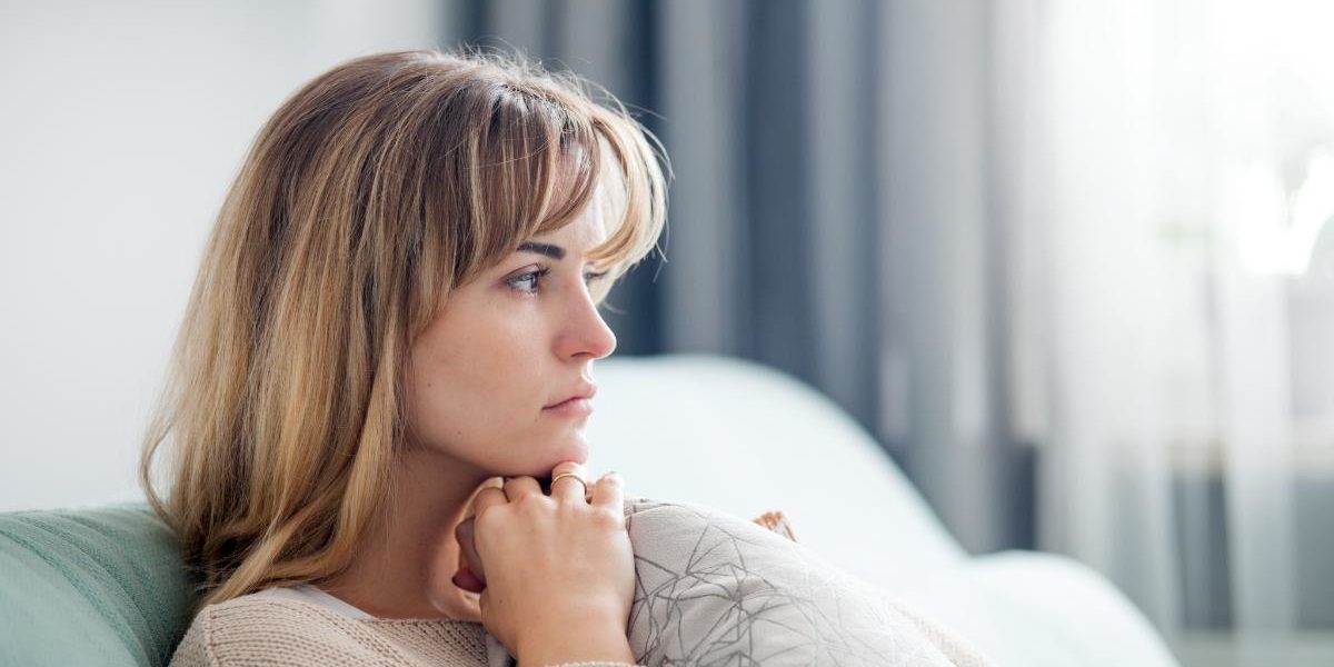 a woman sitting on couch thinking about needing help for borderline personality disorder